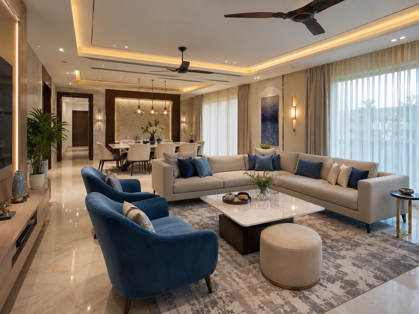 A luxurious living room in Delhi NCR featuring a beige sectional sofa, two striking glacier blue velvet armchairs, and a marble coffee table under warm cove lighting.