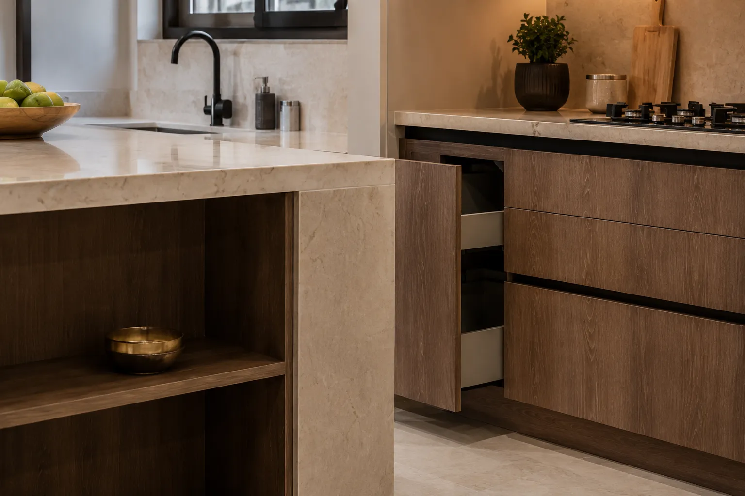 Close-up of modular kitchen lower cabinets with a wood-grain finish, showing a partially open drawer with a white interior below a light stone countertop and black sink faucet.