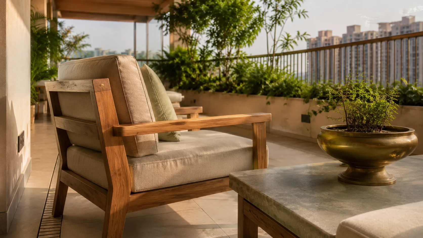 Close-up of a wooden armchair with neutral cushions next to a stone-topped coffee table holding a brass planter.